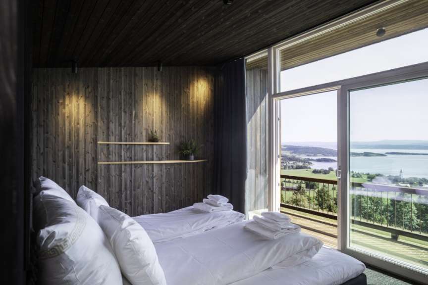 Ein Schlafzimmer mit zwei Betten und einem großen Fenster mit Blick auf einen See