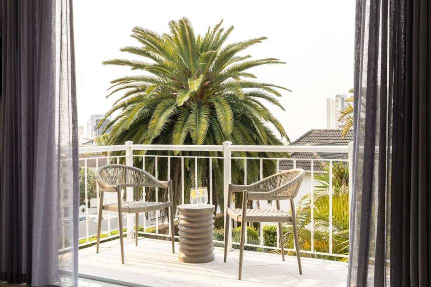 Ein Balkon mit zwei Stühlen und einem Tisch mit einer Palme im Hintergrund