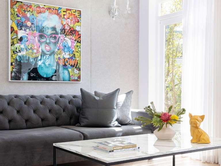 Ein Wohnzimmer mit einem Gemälde an der Wand und einem Couchtisch