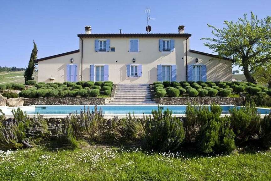 Ein großes weißes Haus mit blauen Fensterläden und einem Pool davor