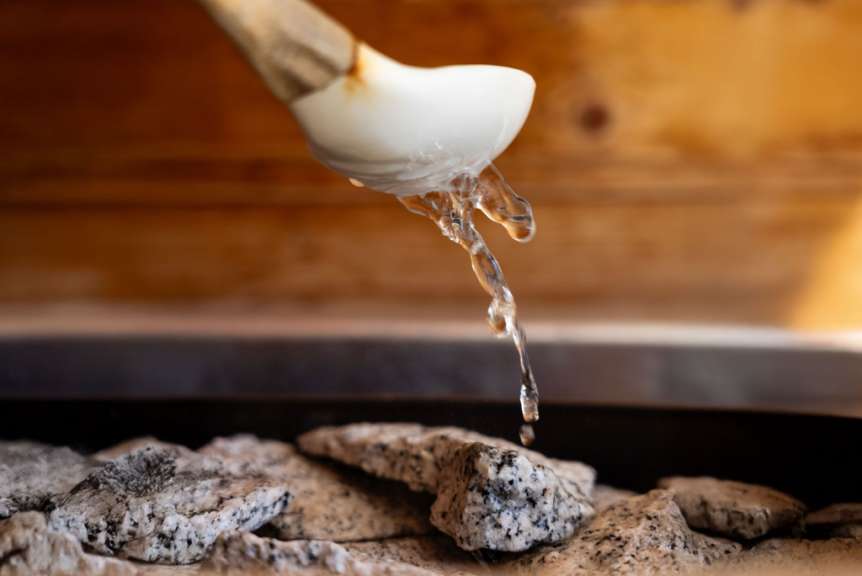 Wasser fließt aus einer weißen Schüssel in eine Sauna