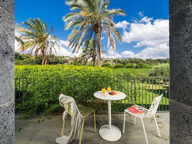 Ein Tisch und Stühle auf einem Balkon mit Palmen im Hintergrund