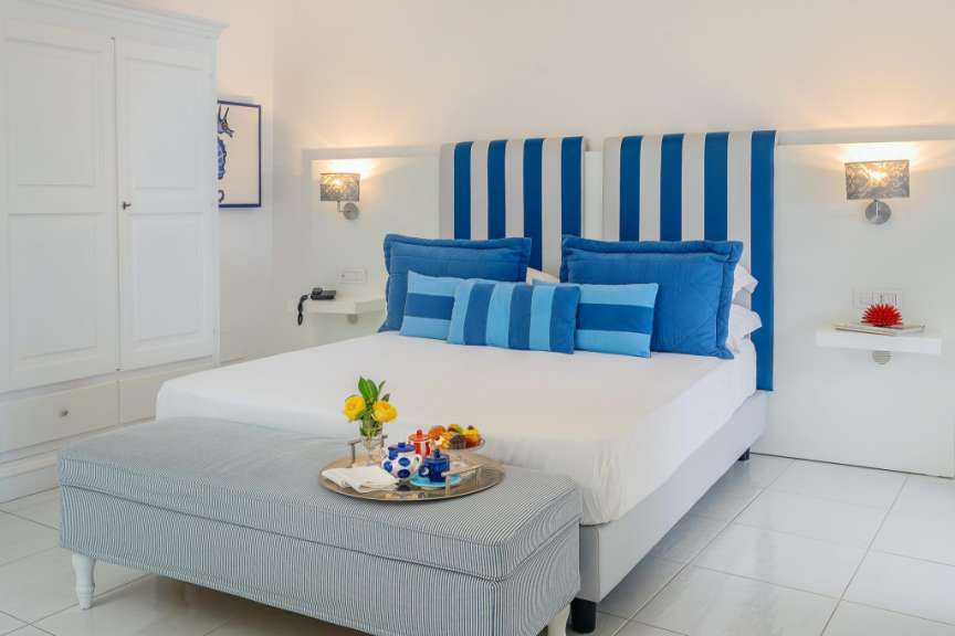 Ein weißes Bett mit blauen Kissen und einem blau-weiß gestreiften Kopfteil