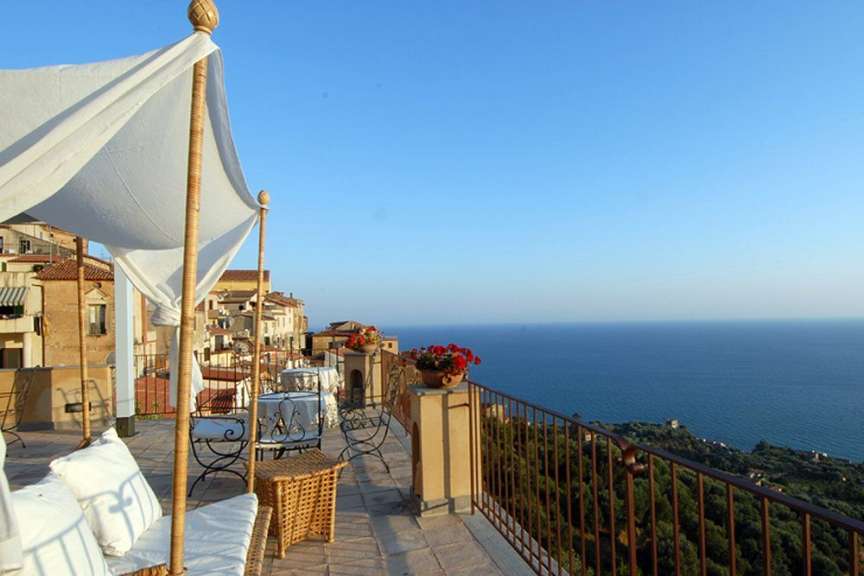 Ein Balkon mit einem weißen Zelt und einem Tisch und Stühlen mit Blick auf das Meer