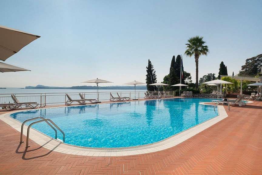 Ein großer Swimmingpool mit Liegestühlen und Sonnenschirmen umgeben