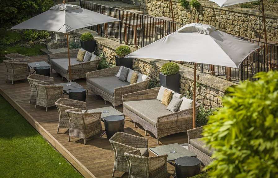 Eine Terrasse mit Couch und Stühlen und Regenschirmen