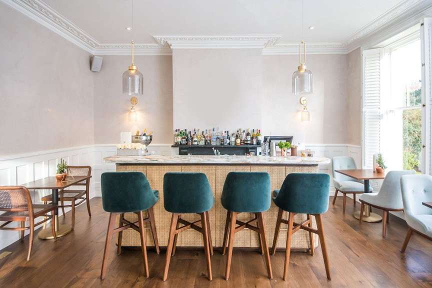 Eine Bar mit grünen Hockern und einem Tisch dahinter