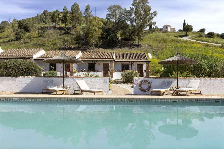 Ein Pool mit Liegestühlen und Sonnenschirmen vor einem Haus