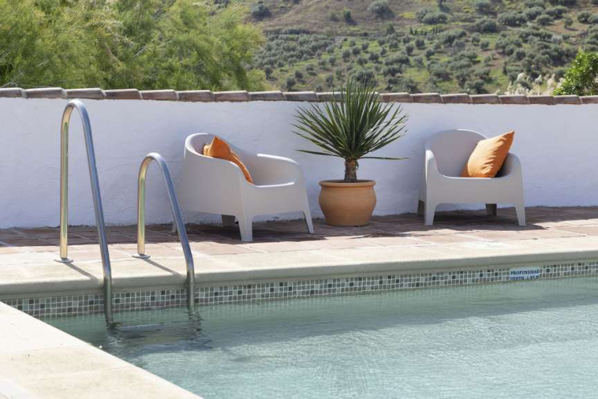 Ein Swimmingpool mit zwei Stühlen und einer Pflanze