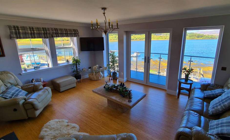 Ein Wohnzimmer mit vielen Fenstern und Blick auf den Ozean