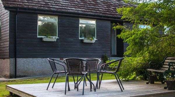 Ein schwarzes Haus mit einem Tisch und Stühlen davor
