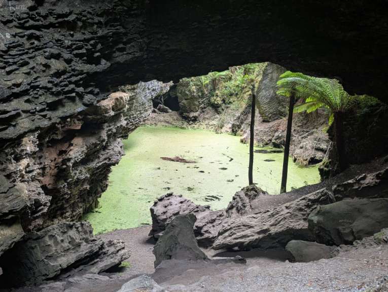 Eine Höhle mit einem grünen Teich in der Mitte