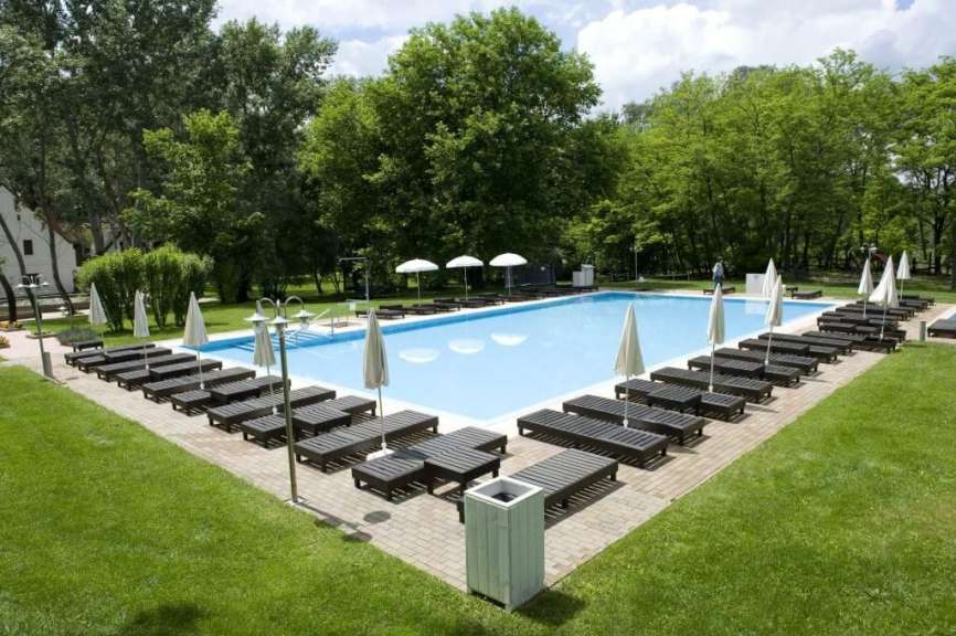 Liegestühle und Sonnenschirme umgeben einen großen Swimmingpool
