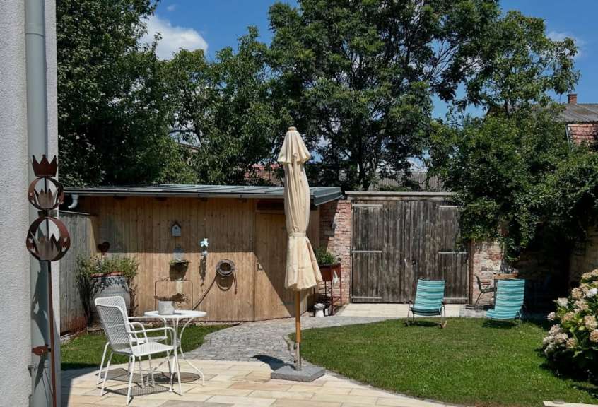 Ein Garten mit einem Tisch und Stühlen und einem Regenschirm