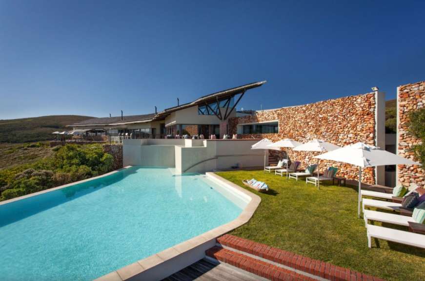 Ein großes Haus mit einem Pool und Liegestühlen davor