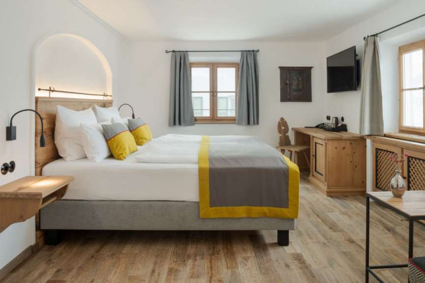 Ein modern eingerichtetes Schlafzimmer mit einem Doppelbett, einem Holztisch und einem Fernsehgerät.