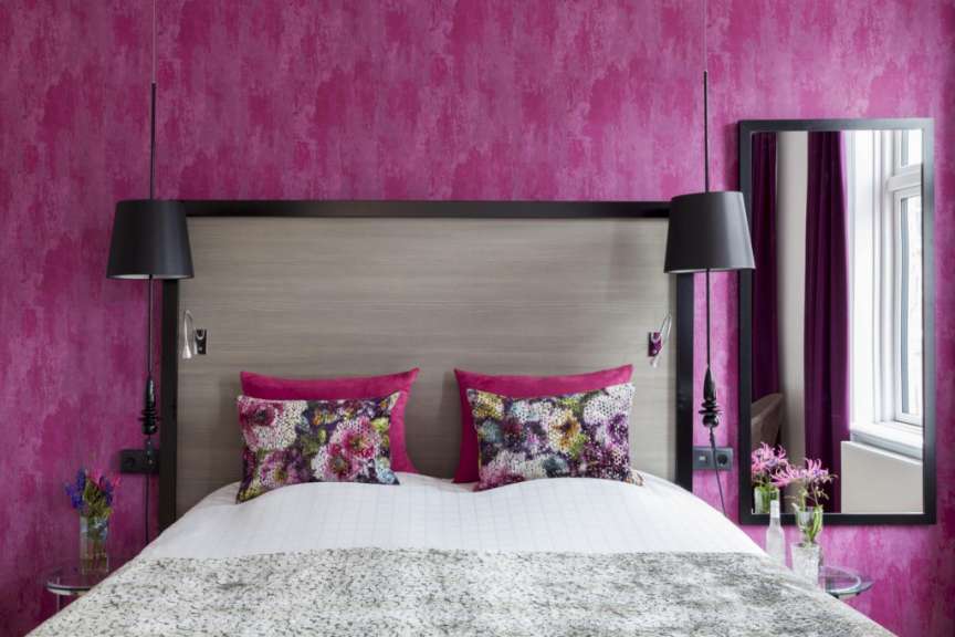 Ein Schlafzimmer mit rosa Wänden und einem Bett