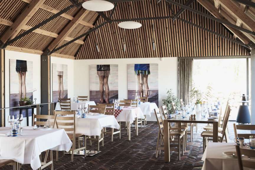 Ein Esszimmer mit Tischen und Stühlen und Gemälden an den Wänden