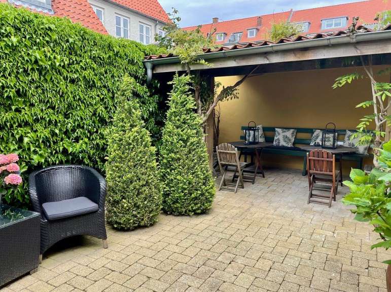 Eine Terrasse mit Stühlen und einem Tisch mit Kissen darauf