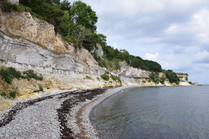 Ein felsiges Ufer mit einem weißen Felsen im Hintergrund