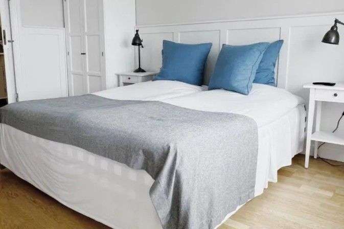 Ein Bett mit blauen Kissen und einer grauen Decke