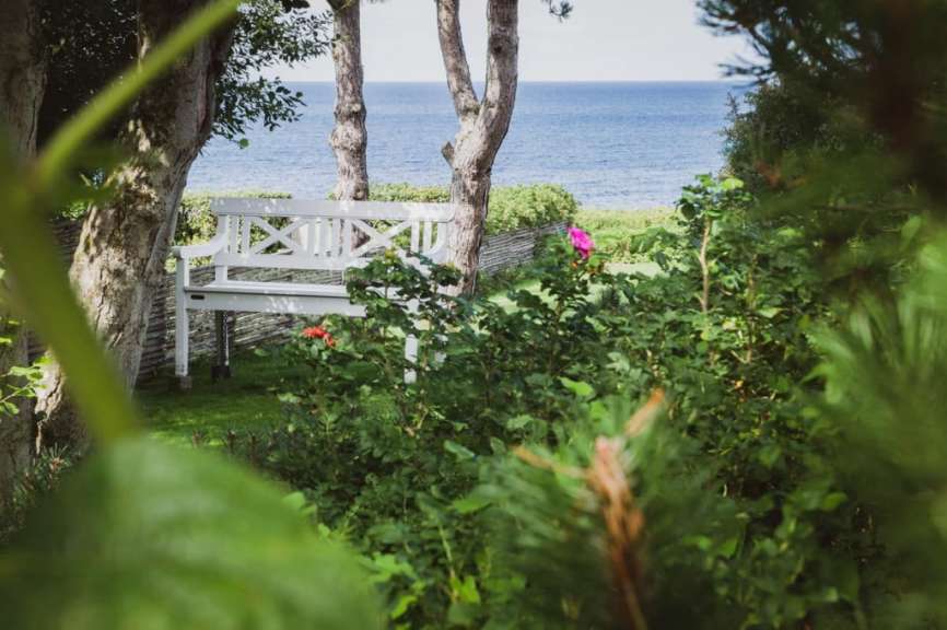 Eine weiße Bank in einem Garten mit Blick auf das Meer
