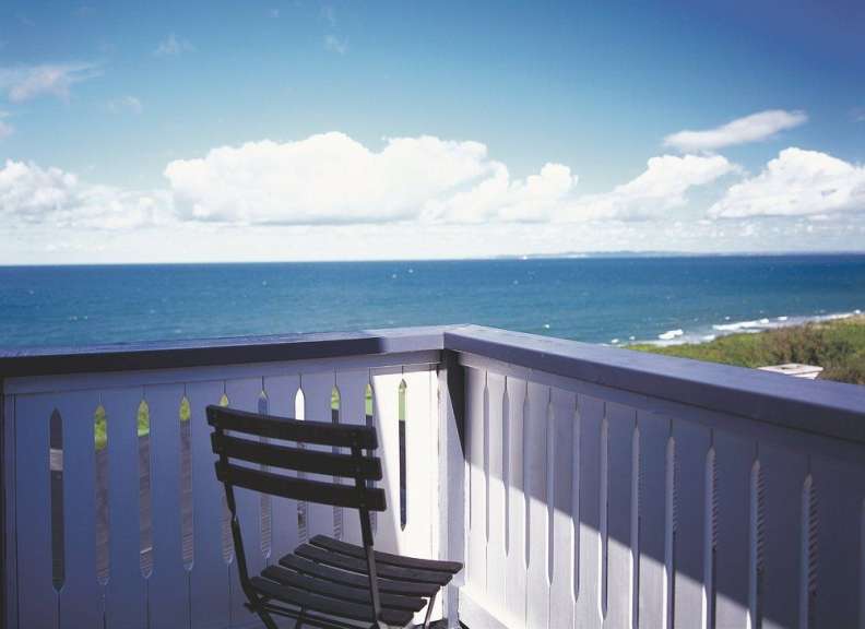 Ein Stuhl sitzt auf einem Balkon mit Blick auf das Meer