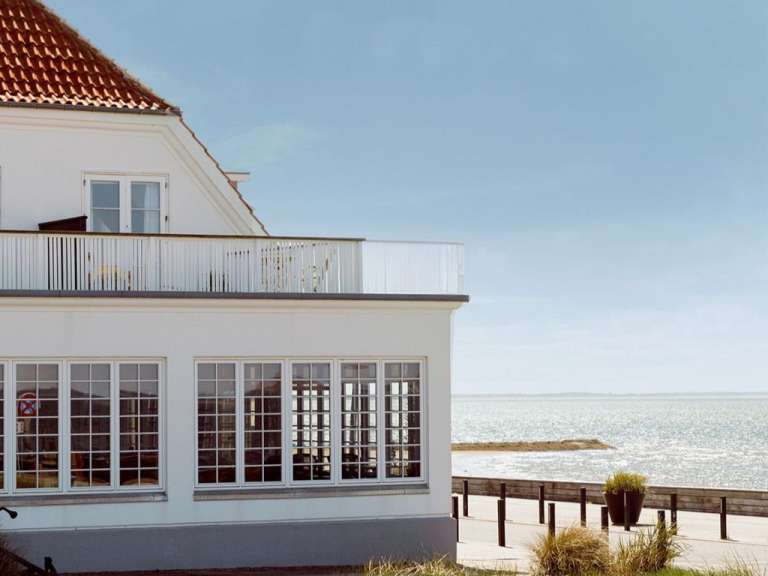 Ein weißes Haus mit vielen Fenstern und einem Balkon mit Blick auf das Meer