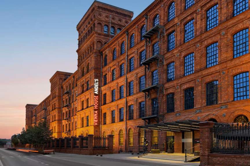 Ein eindrucksvolles Backsteingebäude mit roten Neonschildern ragt in den Abendhimmel.