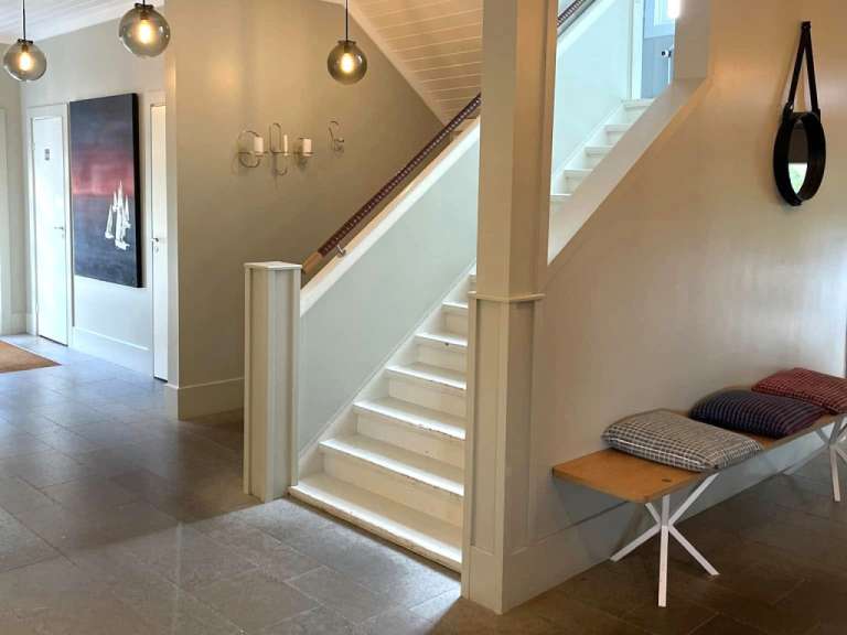 Ein Flur mit weißen Treppen und einer Bank mit Kissen darauf