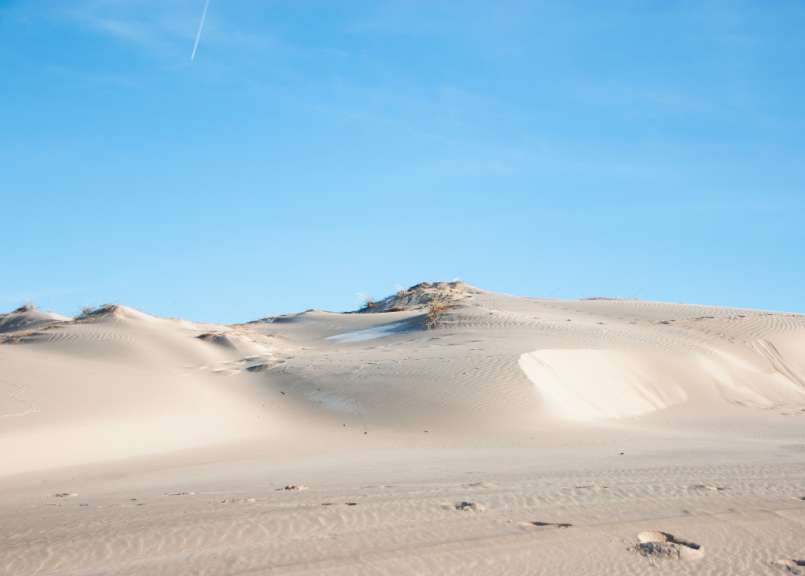 Eine Sanddüne mit einem blauen Himmel im Hintergrund
