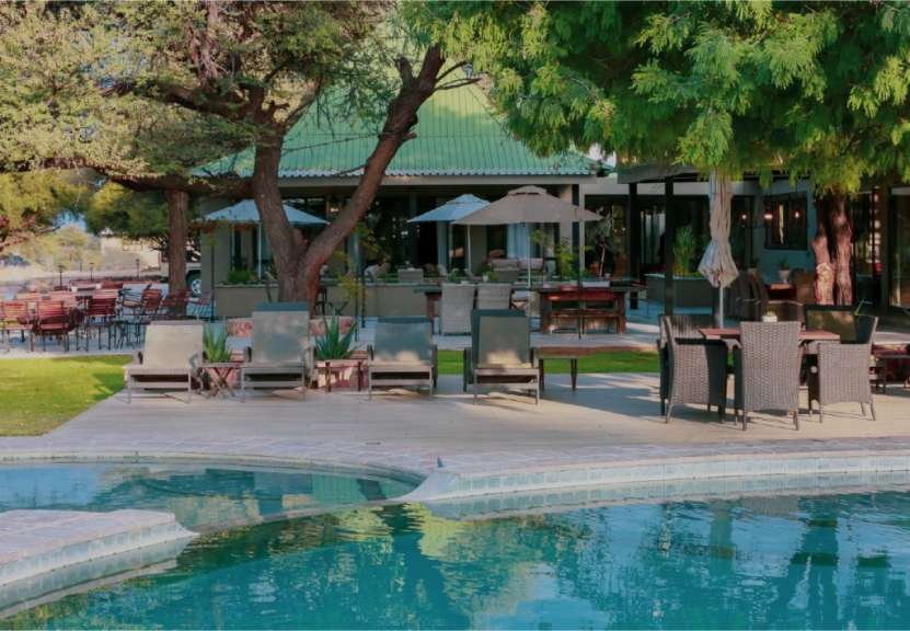 Liegestühle und Tische stehen um einen Swimmingpool