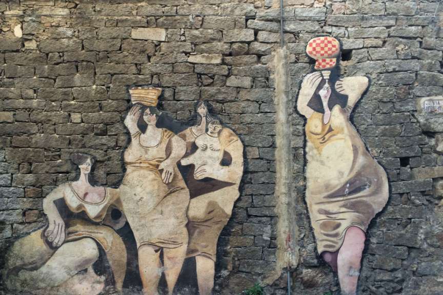Ein Gemälde an einer Backsteinmauer zeigt eine Gruppe von Frauen