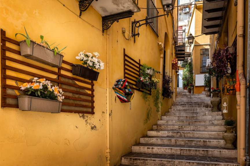 Eine schmale Gasse mit Treppen und Blumenkästen an der Wand