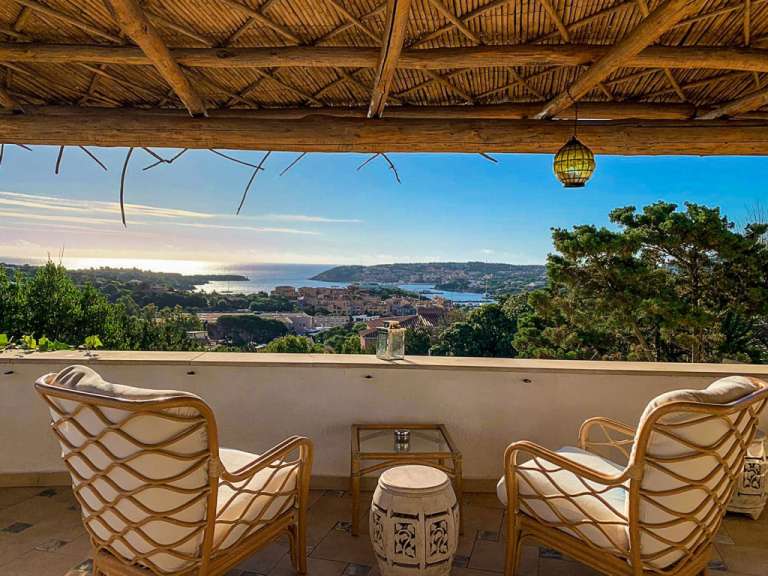 Zwei Stühle sitzen auf einem Balkon mit Blick auf das Meer