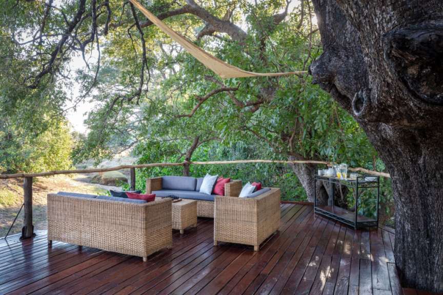 Eine Couch und zwei Stühle sitzen auf einem Holzdeck