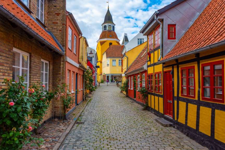 Eine schmale Straße mit bunten Häusern und einer Kirche im Hintergrund