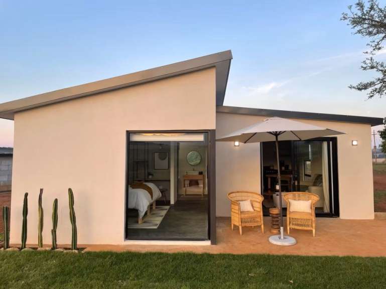 Ein kleines Haus mit einem großen Fenster und einem weißen Regenschirm