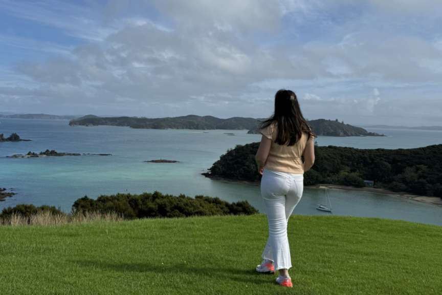 Eine Frau steht auf einem Hügel mit Blick auf das Meer