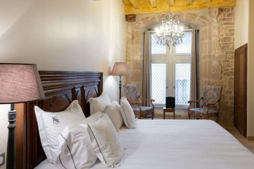 Ein Schlafzimmer mit einem Bett und zwei Stühlen und einem Kronleuchter