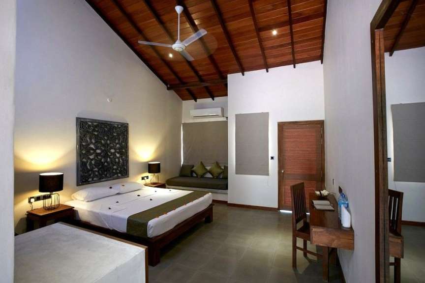 Ein stilvoll eingerichtetes Schlafzimmer mit Doppelbett, Deckenventilator und Holzbalkendecke.