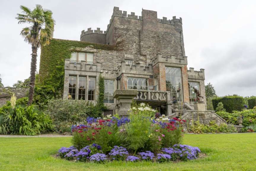 Ein großes Schloss mit vielen Fenstern und einem Blumenbeet vorne