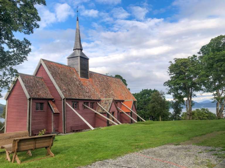 Eine kleine rote Kirche auf einem Hügel mit Blick auf einen See