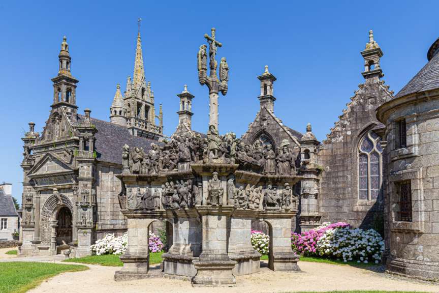 Eine Kirche mit einem Kreuz und vielen Statuen davor