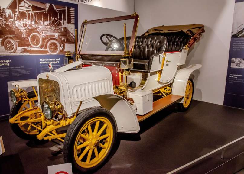 Ein altes weißes Auto mit gelben Rädern in einem Museum