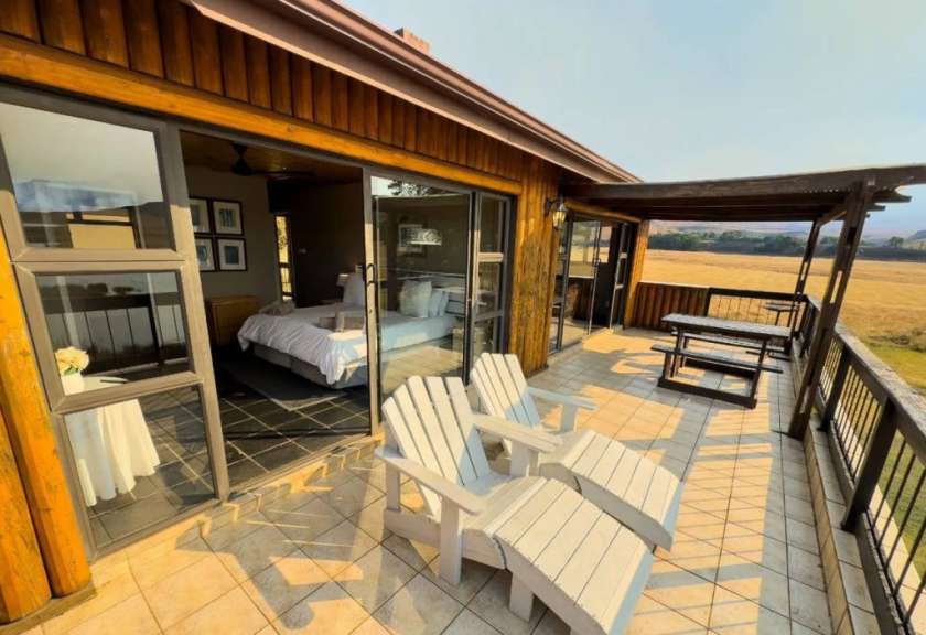 Ein Schlafzimmer mit einem Bett und zwei Stühlen auf einem Balkon