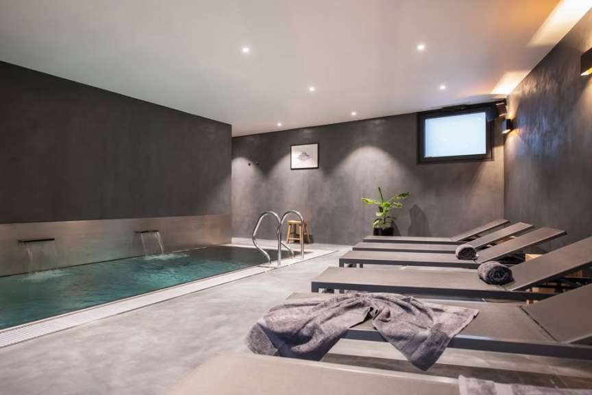 Liegestühle neben einem Pool mit einem Fernseher an der Wand