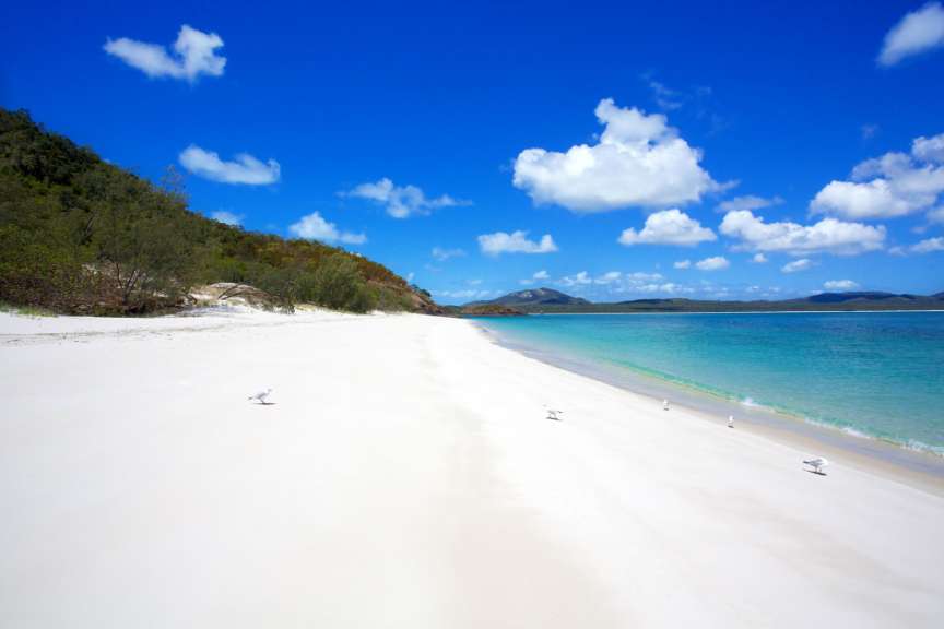 Ein Strand mit weißem Sand und blauem Wasser