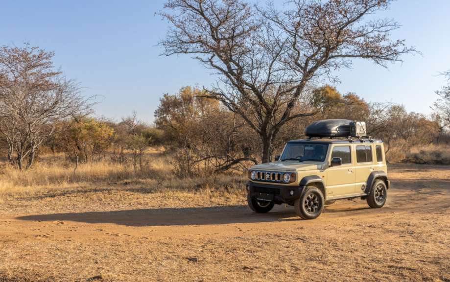 Ein brauner suzuki-jeep fährt auf einer unbefestigten straße