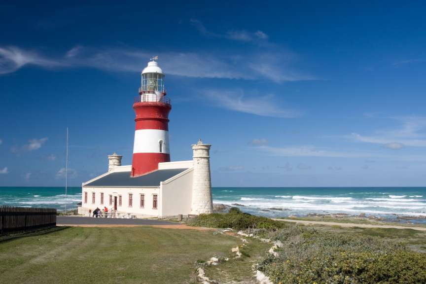 Ein rot-weißer Leuchtturm steht auf einer Klippe über dem Ozean